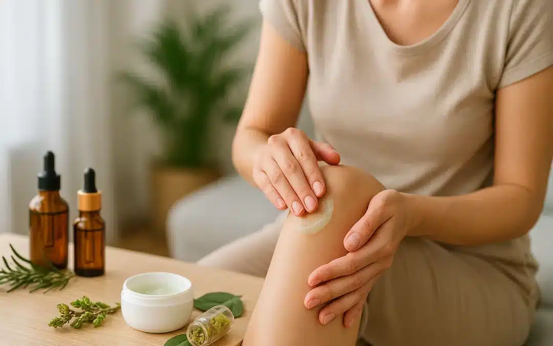 Femme massant son genou avec un gel naturel aux plantes, accompagnée d’huiles essentielles et bourgeons de gemmothérapie sur une table en bois.